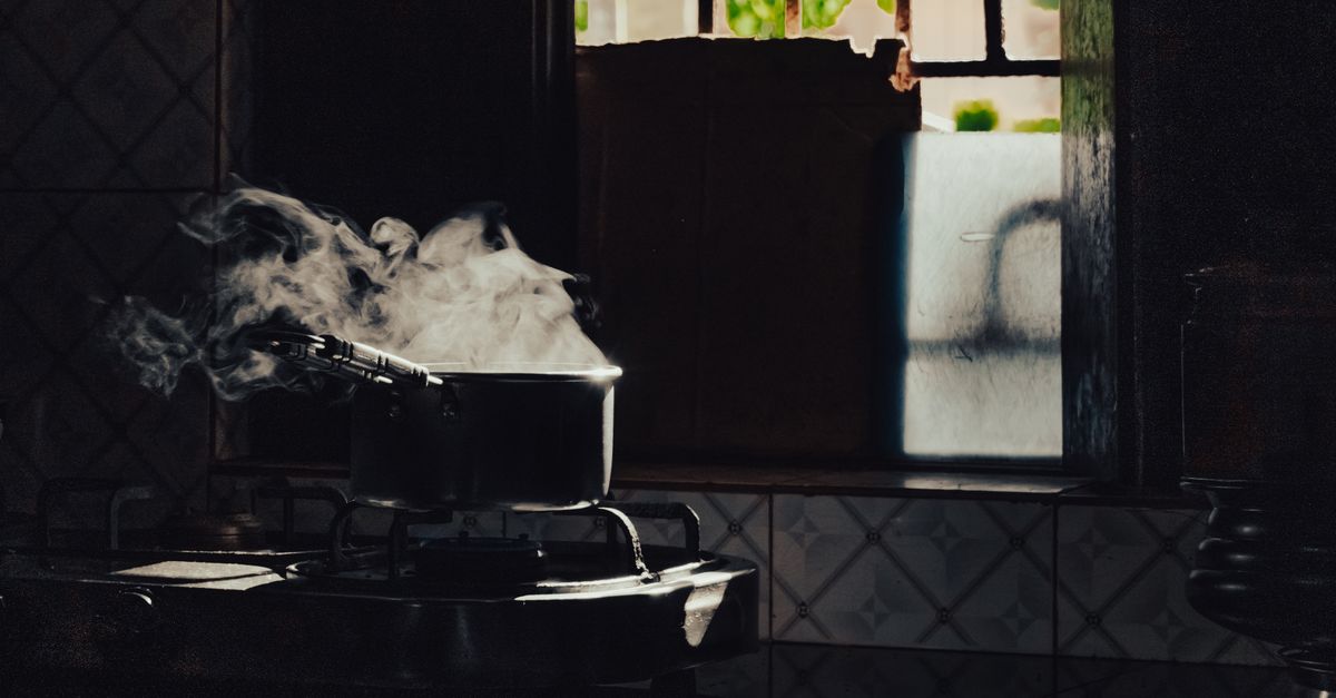 Ollas humeantes sobre una cocina de gas junto a una ventana con luz natural entrando.