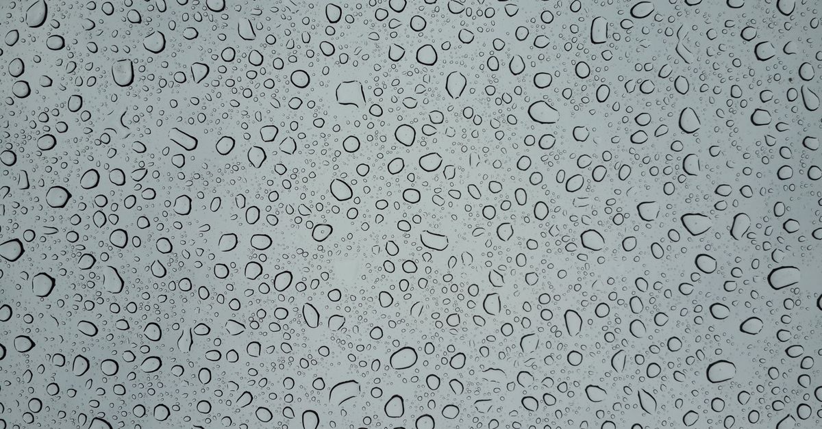 Gotas de condensación cubriendo una superficie de vidrio gris, similar a las que se forman en los azulejos del baño.