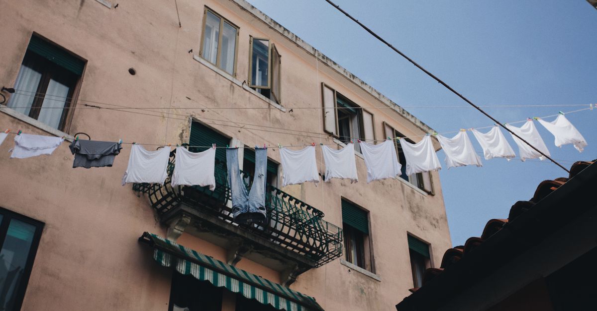 Ropa blanca tendida al sol en una cuerda frente a las ventanas de un edificio antiguo
